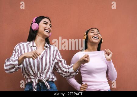 Jeunes femmes latines heureuses qui dansent et écoutent de la musique avec casque sans fil Banque D'Images