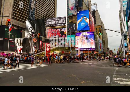 Les gens traversent la rue à Times Square lors d'une soirée d'été très animée Banque D'Images