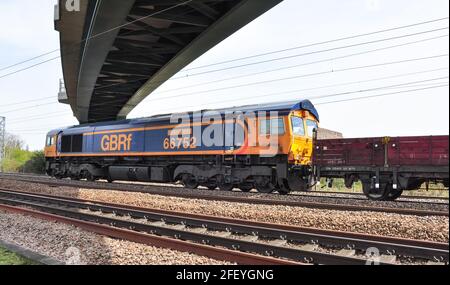 Classe 66, près de Hitchin, fournissant une assistance arrière pour un long train lourd de ballasts et de traverses en béton pour le remodelage de la Croix du Roi de Londres Banque D'Images