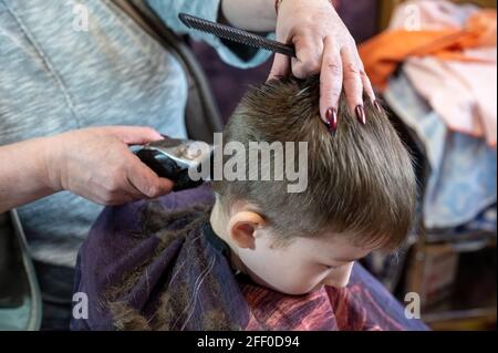 Coupe de cheveux pour petit garçon à la maison par maintien Banque D'Images