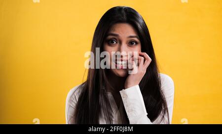 Une jeune femme excitée se mâche sur ses ongles Banque D'Images