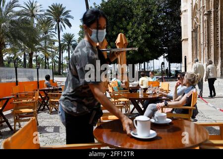 Palma, Espagne. 24 avril 2021. Maria, serveuse du bar sa Llotja, sert du café à ses clients en plein air. Sur Majorque, de nouvelles relaxations de Corona s'appliquent depuis 24.04.2021. En fait, les restaurateurs sont autorisés à ouvrir les espaces extérieurs jusqu'à 5 h, les espaces intérieurs doivent rester fermés. Du lundi au jeudi, les établissements sont également autorisés à servir des clients sur les terrasses entre 20 h et 22 h 30. Credit: Clara Margais/dpa/Alay Live News Banque D'Images