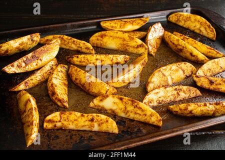 Feuilles de pommes de terre crues sur une plaque de cuisson : frites de pommes de terre en coin roulées non cuites sur une plaque de cuisson Banque D'Images