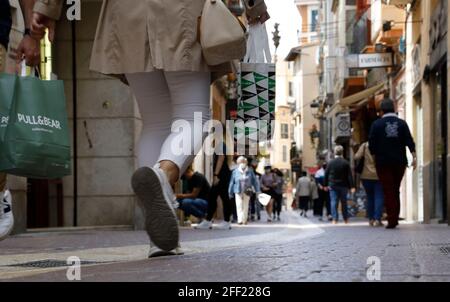 Palma, Espagne. 24 avril 2021. Les clients qui ont des sacs de shopping traversent une rue commerçante. À Majorque, de nouvelles relaxations de Corona s'appliquent depuis 24.04.2021. Les magasins et les centres commerciaux sont ouverts, sont autorisés selon la journée et le lieu entre 30 et 75 pour cent de la capacité des clients. Les magasins qui ne servent pas les besoins quotidiens sont autorisés à ouvrir jusqu'à 21.00 heures. Credit: Clara Margais/dpa/Alay Live News Banque D'Images