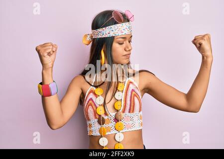 Belle femme hispanique portant le style bohème et hippie montrant les muscles des bras souriant fier. Concept de forme physique. Banque D'Images