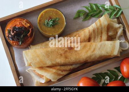 Crêpes croustillantes faites de riz et de lentilles. Servi avec un condiment aux tomates et un sambar. Prise de vue sur fond blanc. Banque D'Images