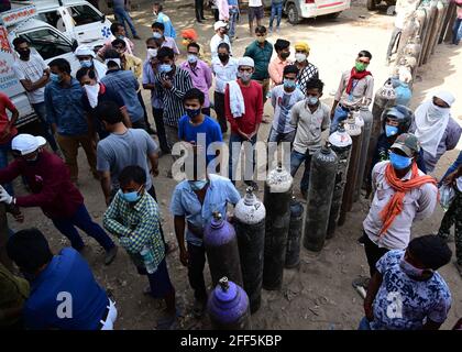 Prayagraj, Uttar Pradesh, Inde. 24 avril 2021. Les membres de la famille qui font la queue pour remplir les bouteilles d'oxygène médicales pour les patients atteints du coronavirus à une station de recharge d'oxygène. Le nombre quotidien de décès par coronavirus en Inde a établi un nouveau record samedi alors que le gouvernement s'est batté pour fournir de l'oxygène aux hôpitaux submergés par les centaines de milliers de nouveaux cas quotidiens. Des files d'attente de patients Covid-19 et de leurs parents craintifs se sont formées en dehors des hôpitaux dans les grandes villes de l'Inde, qui a rapporté près d'un million de nouveaux cas en trois jours. Credit: Prabhat Kumar Verma/ZUMA Wire/Alamy Live News Banque D'Images