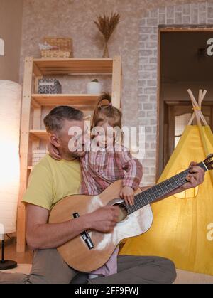 un père heureux joue de la guitare pour sa petite fille. soins et éducation des enfants Banque D'Images