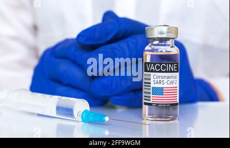 Flacons de vaccins avec drapeaux américains, photo en gros plan du vaccin américain Covid-19, contexte du concept de vaccination avec les mains du médecin dans des gants bleus Banque D'Images