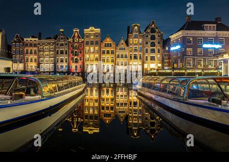 Amsterdam Damrak architecture hollandaise traditionnelle de nuit. Faites des croisières en bateau au premier plan. Banque D'Images