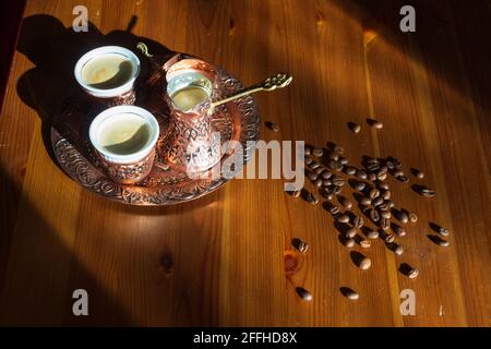Café turc servi dans une tasse de cuivre et une cafetière. Grains de café sur une table en bois brun. Banque D'Images