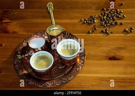 Café turc servi dans une tasse de cuivre et une cafetière. Grains de café sur une table en bois brun. Banque D'Images