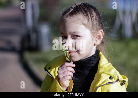 Portrait d'une fille qui renifle des fleurs un jour ensoleillé au début du printemps. Banque D'Images