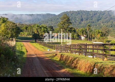 Route de ferme avec champ, montagnes et forêt en arrière-plan, Ivoti, Rio Grade do Sul, Brésil Banque D'Images