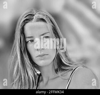 portrait frontal noir et blanc doux d'une très jolie jeune femme avec des cheveux longs. et une raie intermédiaire. Elle ne regarde pas l'appareil photo. Couleur douce gris Banque D'Images