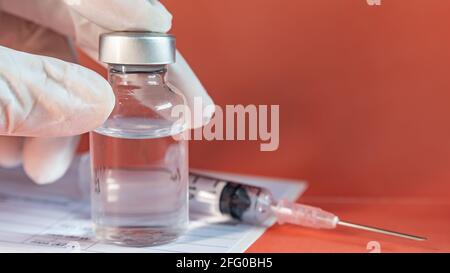 Un flacon de vaccin dans une main avec un gant Banque D'Images