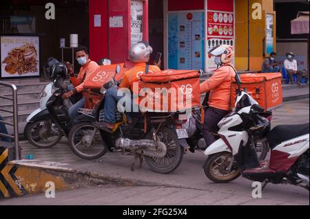 En raison d'une récente épidémie de COVID - 19 sur les marchés et les usines de vêtements, Le gouvernement cambodgien a imposé un verrouillage. Ici, les chauffeurs de motos qui livreurs de vivres ont une réunion improvisée sur la façon de faire passer leur nourriture par les postes de contrôle et les barrages routiers de la police. De nombreux Cambodgiens sont en quarantaine et ne sont pas autorisés à quitter leur rue pour faire du shopping pendant la pandémie du coronavirus. Stueng Meanchey, Phnom Penh, Cambodge. 15 avril 2021. © Kraig Lieb Banque D'Images