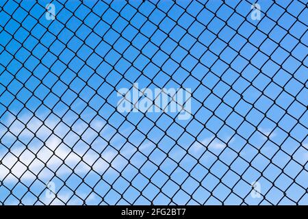 Image abstraite montrant un treillis d'une clôture en chaîne couvrant tout le ciel bleu. Polyvalent pour des concepts comme le manque de liberté, les causes humanitaires, Banque D'Images