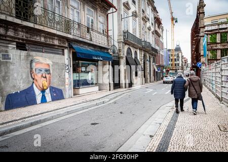 Porto, Portugal. 24 avril 2021. Deux personnes se promo devant un graffiti qui dépeint Donald Trump. Le Portugal est à la 3ème étape du plan de déconditionnement mais les magasins, les restaurants et les cafés sont toujours fermés le week-end durant l'après-midi. Crédit : SOPA Images Limited/Alamy Live News Banque D'Images