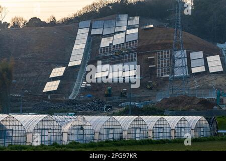Panneaux solaires installés à flanc de colline surplombant la rangée de serres Banque D'Images