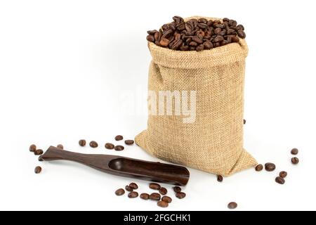 Grains de café. Sac de jute avec grains de café torréfiés et spatule à café près. Isolé sur fond blanc. Banque D'Images