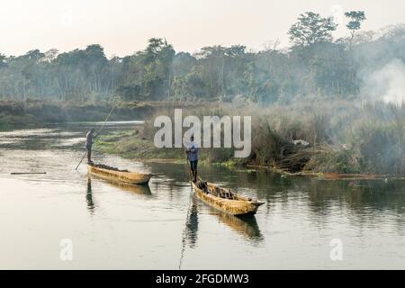 Deux hommes poussent des canots ou des bateaux sur la rivière dans le parc national de Chitwan, au Népal Banque D'Images