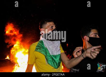 Gaza, Palestine. 24 avril 2021. Les Palestiniens brûlent la roue et lèvent le drapeau palestinien lors d'une manifestation à l'ouest de la ville de Gaza en faveur des Palestiniens de Jérusalem-est. Depuis le début du ramadan, le 13 avril, les tensions se sont élevées à Jérusalem-est, dans un premier temps à la suite de l'interdiction par les autorités israéliennes de se réunir autour de la porte de Damas de la vieille ville, où les Palestiniens ont tendance à se réunir dans la soirée pendant le ramadan. Les tensions se sont encore exacerbées jeudi soir, lorsque les extrémistes juifs ont défilé près de la vieille ville de Jérusalem-est pour crier « mort aux Arabes Banque D'Images