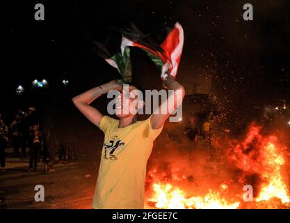 Gaza, Palestine. 24 avril 2021. Les Palestiniens brûlent la roue et lèvent le drapeau palestinien lors d'une manifestation à l'ouest de la ville de Gaza en faveur des Palestiniens de Jérusalem-est. Depuis le début du ramadan, le 13 avril, les tensions se sont élevées à Jérusalem-est, dans un premier temps à la suite de l'interdiction par les autorités israéliennes de se réunir autour de la porte de Damas de la vieille ville, où les Palestiniens ont tendance à se réunir dans la soirée pendant le ramadan. Les tensions se sont encore exacerbées jeudi soir, lorsque les extrémistes juifs ont défilé près de la vieille ville de Jérusalem-est pour crier « mort aux Arabes Banque D'Images