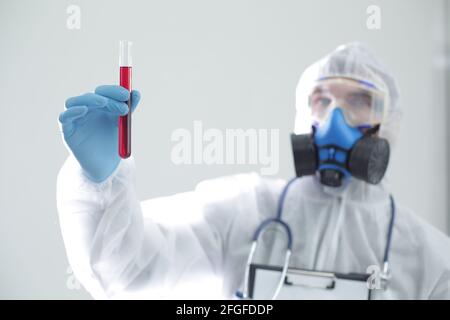 Un homme en costume médical de protection tient un tube à essai dans ses mains. Le concept de vaccins ouverts contre le coronavirus Banque D'Images