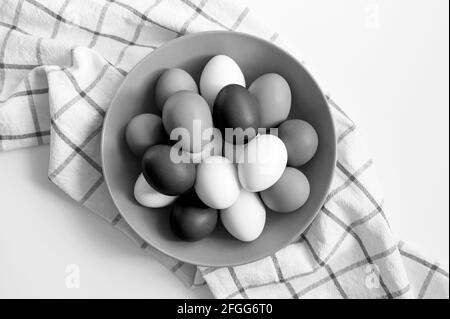 œufs de poulet de couleur blanche et noire dans une assiette une serviette de cuisine à carreaux sur une table blanche Banque D'Images