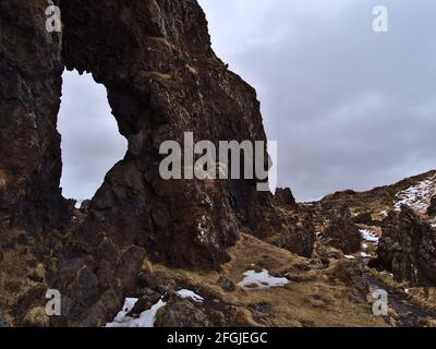 Formations rocheuses volcaniques (arche naturelle) à la plage de Djúpalónssandur sur la côte ouest de la péninsule de Snæfellsnes, en Islande en hiver avec de la neige. Banque D'Images