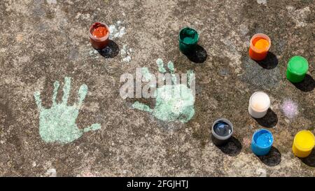 Les empreintes de main des enfants sur les contenants de peinture en béton et colorés. Créativité, arts et artisanat, enfants intégration sensorielle art thérapie résumé conce Banque D'Images