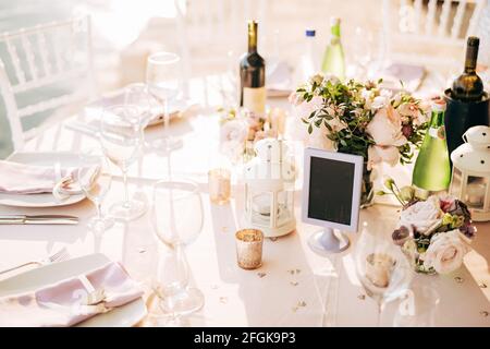 Table ronde joliment décorée avec boissons, fleurs et un panneau vierge au centre. Décoration dans des tons pastel Banque D'Images