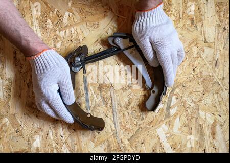 les mains des hommes avec gants sont des cales de frein de tambour de voiture démontées sur une feuille de contreplaqué osb. flat lay, vue de dessus Banque D'Images