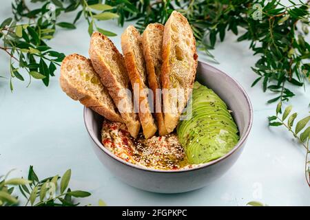 Bol de houmous avec tranches d'avocat et de toasts Banque D'Images