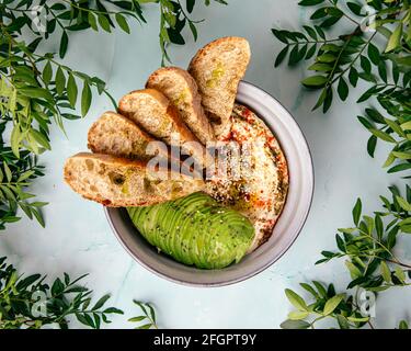 Bol de houmous avec tranches d'avocat et de toasts Banque D'Images