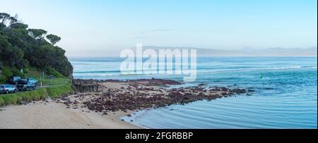 Un panorama tôt le matin des cavaliers à bord en attente de la Faites une vague à droite à Bar Beach à Merimbula sur la nouvelle Pays de Galles du Sud côte sud de l'Australie Banque D'Images