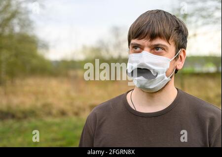 la journée des pères au cours du concept de quarantaine covid-19. portrait d'un jeune homme européen dans un masque de protection et une moustache en papier sur le fond de Banque D'Images