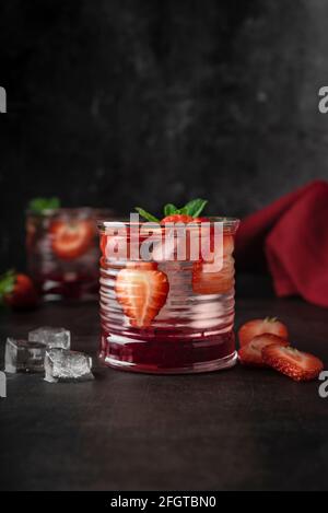 bar magazine concept. cocktail, boisson avec glace et fraises fraîches. avec feuilles de menthe. touche basse, ambiance sombre Banque D'Images