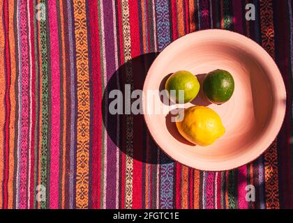 Image en hauteur d'une assiette à soupe rose pastel au citron et il est allumé sur une nappe colorée à rayures au soleil Banque D'Images