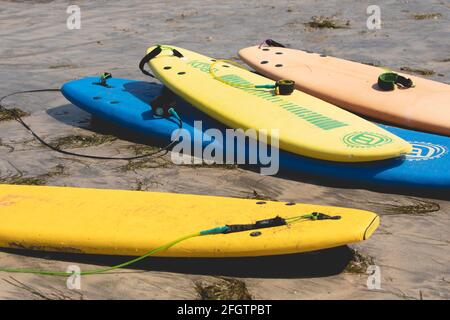 Galice, Espagne - 4 août 2020 : planches de surf de couleurs diverses, empilées et reposant sur le sable sur la rive après une leçon de surf sur la plage de San an Banque D'Images