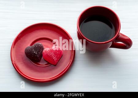 Tasse de café dans une tasse rouge et deux coeurs sur une soucoupe. Concept matin. Banque D'Images