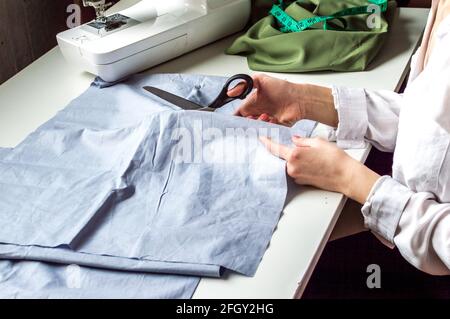 seamstress permet de couper du tissu sur le bureau. Studio sur mesure. Production de vêtements, processus de couture Banque D'Images
