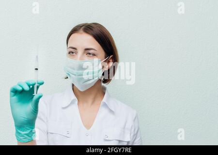Une jeune femme médecin tient une seringue dans sa main et la regarde. Concept d'antibiotiques Banque D'Images