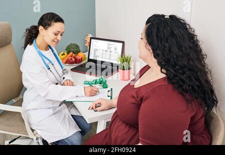 Obésité, poids malsain. Nutritionniste calculant l'indice de masse corporelle de la femme grasse pour le traitement de l'obésité Banque D'Images