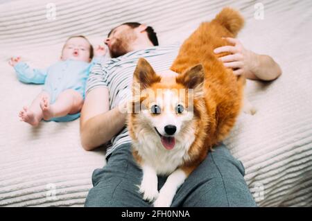 Papa et bébé sont couchés sur le lit avec le chien. Portrait en gros plan Banque D'Images