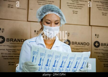 Atyrau, Kazakhstan - 21 mai 2012 : usine de production de seringues Brando. Jeune femme asiatique dans le masque de contrôle de l'emballage de la seringue. Banque D'Images