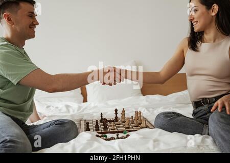 Un jeune couple heureux se secoue les mains au lit avec des échecs. Jeune famille déménapose dans un nouvel appartement Banque D'Images
