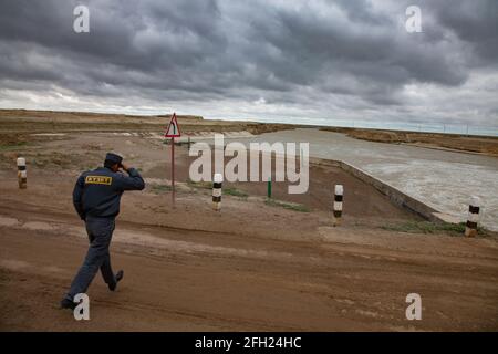 Région de Kzylorda,Kazakhstan:barrage d'Aklak sur la rivière Shardara.Title:Security Guard.Man courir sous un vent fort.eau turbulente et nuages de tempête Banque D'Images