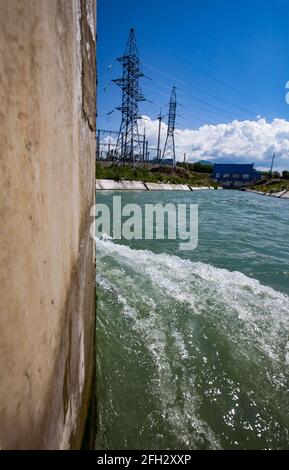 Centrale hydroélectrique. Eau turbulente avant barrage. Mur de sortie de barrage en béton gauche. Ciel bleu, nuages. Région d'Almaty, Kazakhstan Banque D'Images